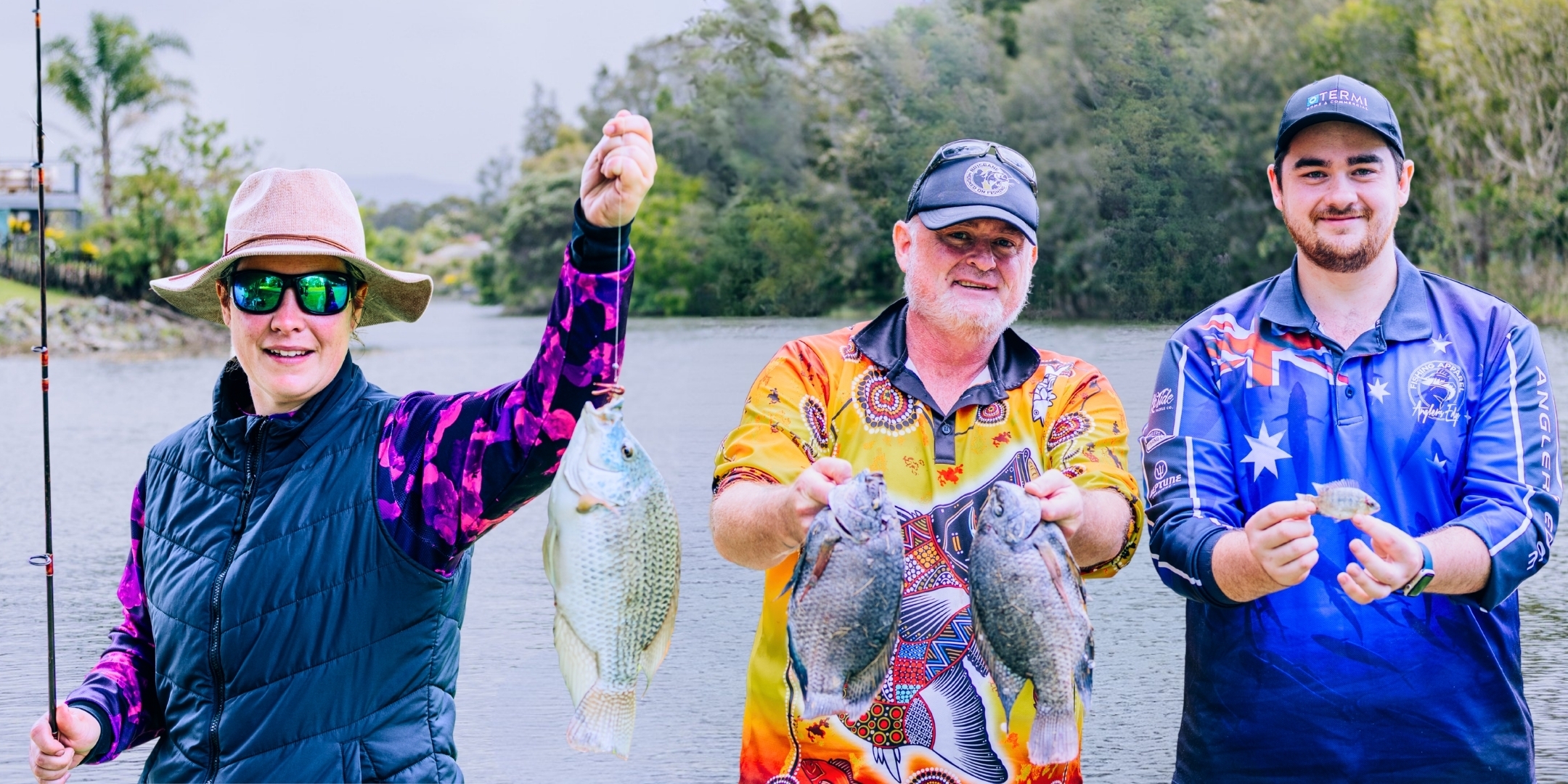 1 woman and 2 men smiling and holding pest fishes that they have catched